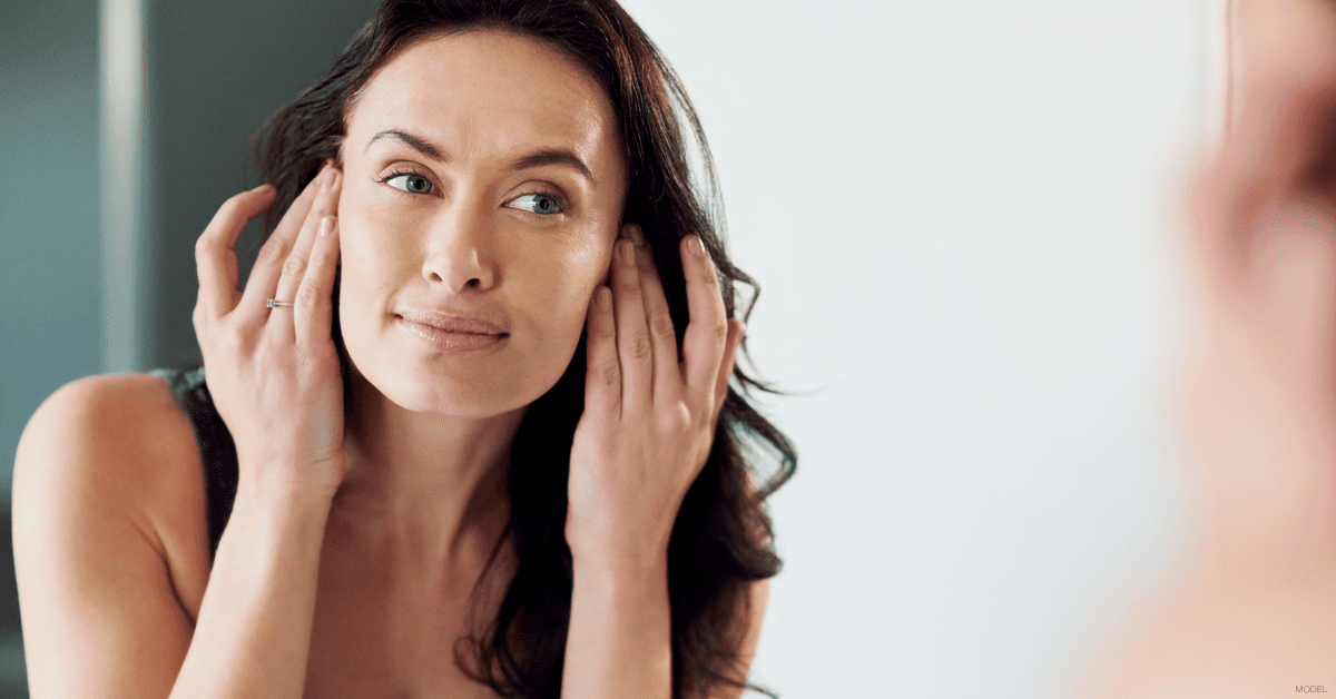 Woman looking at skin in mirror after microneedling treatment in Dallas, TX