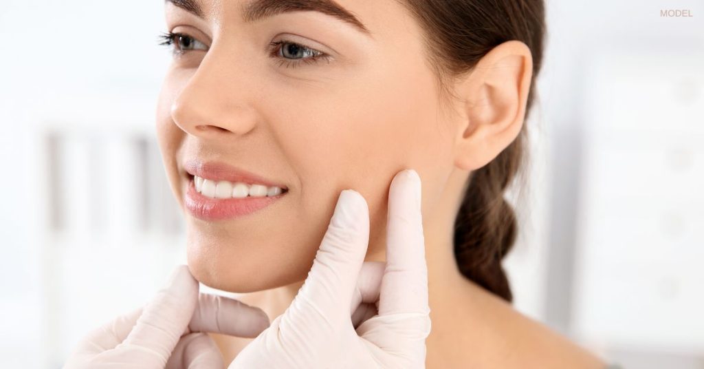 Close up of woman's face with beautiful skin (model) having her face examined by a provider.